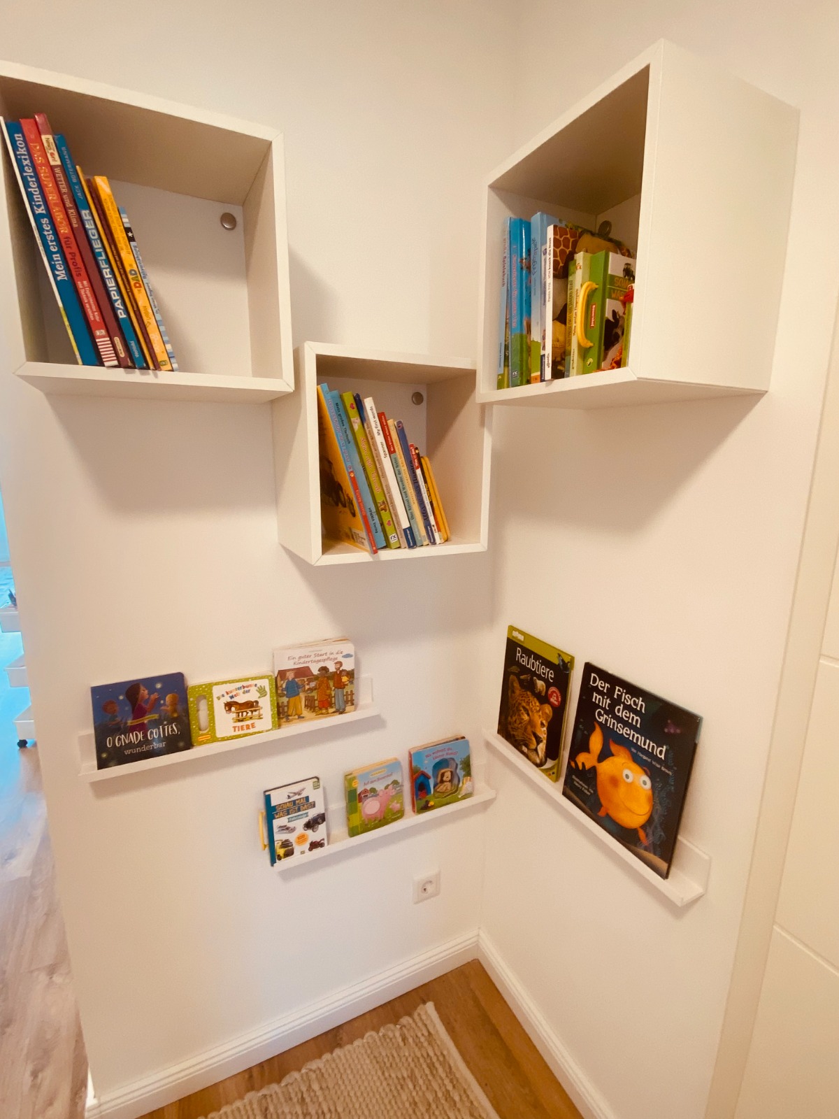 Bücherecke mit Wandregalen voller bunter Kinderbücher auf Kinderhöhe