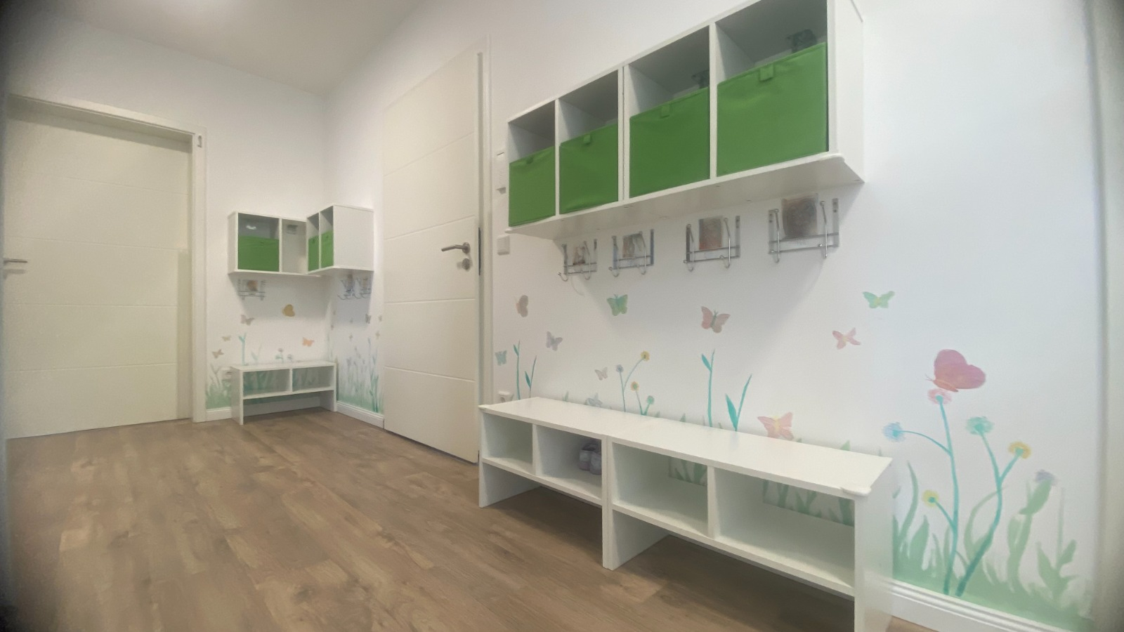 Freundliche Garderobe mit Schmetterlings-Wanddeko, persönlichen Fächern und Namensschildern