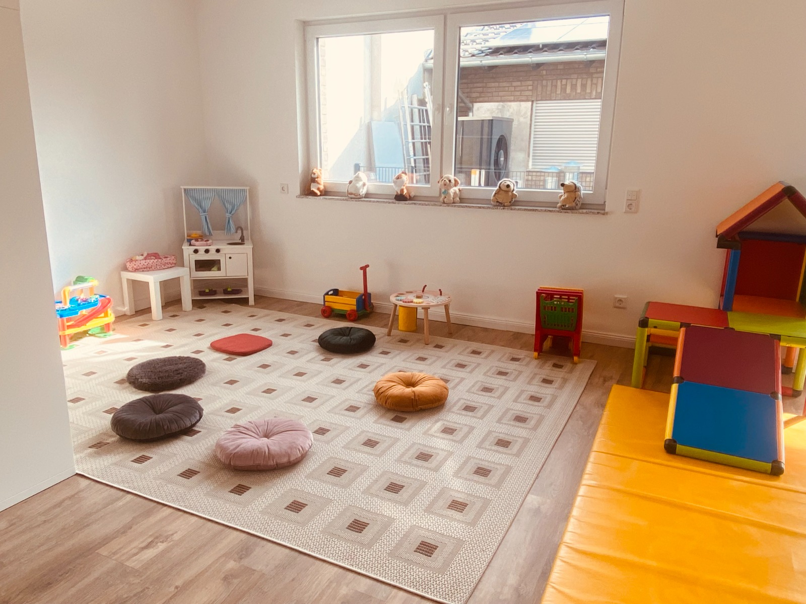 Heller, freundlicher Spielbereich der Christlichen Kindergroßtagespflege mit bunten Sitzkissen, Kinderküche und Spielhaus